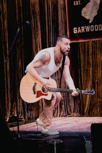 a man playing an acoustic guitar on stage