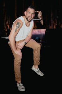 a man sitting on a chair with a tattoo on his chest
