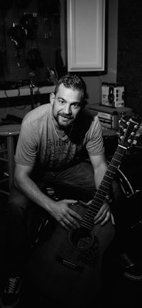 a black and white photo of a man holding an acoustic guitar